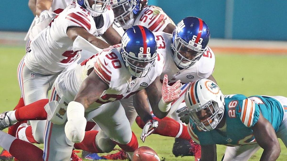 The New York Giants’ Jason Pierre-Paul, with white bandages on his right hand, recovers a fumble in a game against the Miami Dolphins at Sun Life Stadium in Miami Gardens on Dec. 14, 2015 — about four months after doctors at Jackson Memorial Hospital amputated his right index finger following a fireworks accident.