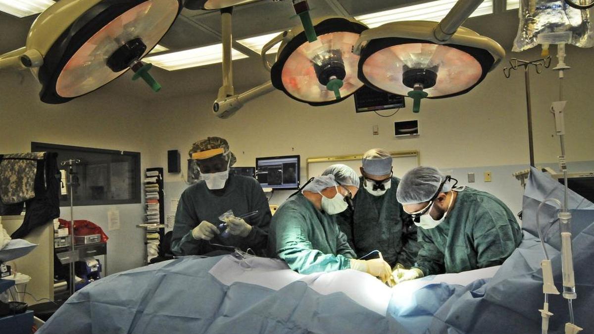 Doctors, along with residents, and nursing staff, operate on a patient in one of Jackson Memorial’s many operating suites.