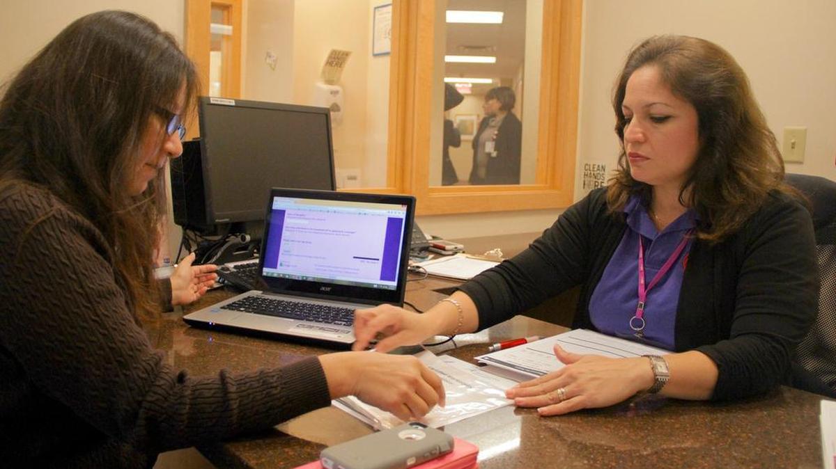 
Velkis Silva, right, a counselor for the Epilepsy Foundation of Florida, helps restaurant server Elisa Flores, left, sign up for a health plan through the Affordable Care Act during open enrollment for 2015. Nearly $10 million in grants were announced Wednesday for Floridians to receive in-person enrollment assistance. 
