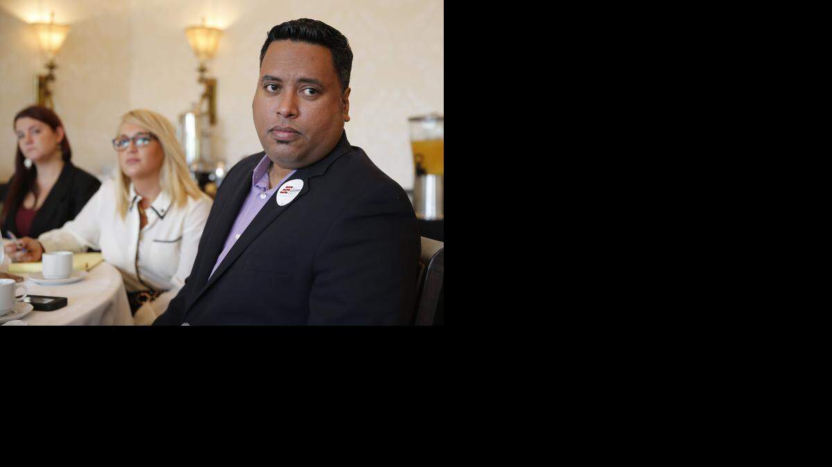 Milton Vazquez, a full-time organizer with Enroll America, listens to speakers at the Coral Gables Country Club during the kickoff of a campaign to sign Floridians to health insurance plans under the Affordable Care Act. The enrollment period begins on Nov. 15. At center is Lili Bach, Florida field director for America Votes.