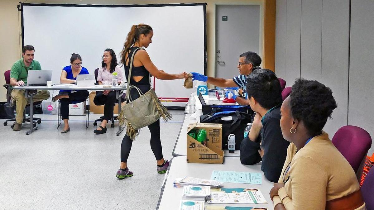 Cristina Montiel hands over a urine sample at a Zika testing center at the Miami Beach Police Department on Tuesday, Sept. 13, 2016. The Florida Department of Health is testing people who live in the Zika transmission zone in Miami Beach for free, provided they show a photo ID indicating they live in the zone, which is bordered between Eighth and 28th Streets, Biscayne Bay to the ocean.