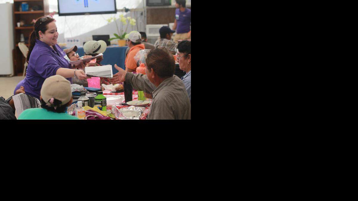 Roxana Galera, (left in purple shirt) director of social services from Epilepsy Foundation of Florida, hands out information about the Affordable Care Act to uninsured Hispanic nursery workers during their lunch break at Plants In Design, a bromeliad nursery in Homestead in 2013.
