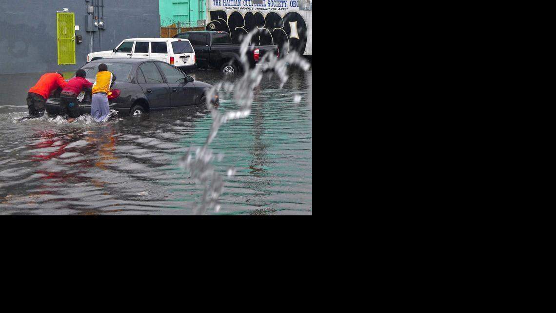 
Locals help a motorist by pushing his car through the flooded street. Several inches of rain fell in S. Florida causing massive flooding through the streets of Little Haiti near the Little Haiti Cultural Complex on Saturday, Feb. 28, 2015.
