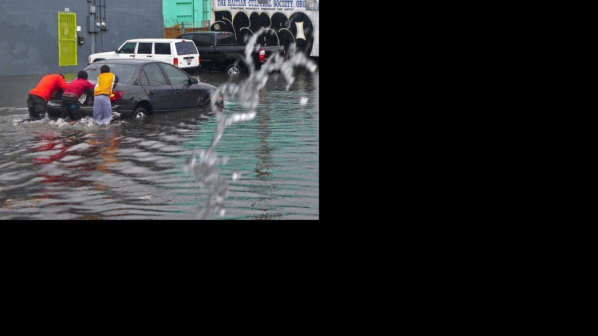 
Locals help a motorist by pushing his car through the flooded street. Several inches of rain fell in S. Florida causing massive flooding through the streets of Little Haiti near the Little Haiti Cultural Complex on Saturday, Feb. 28, 2015.
