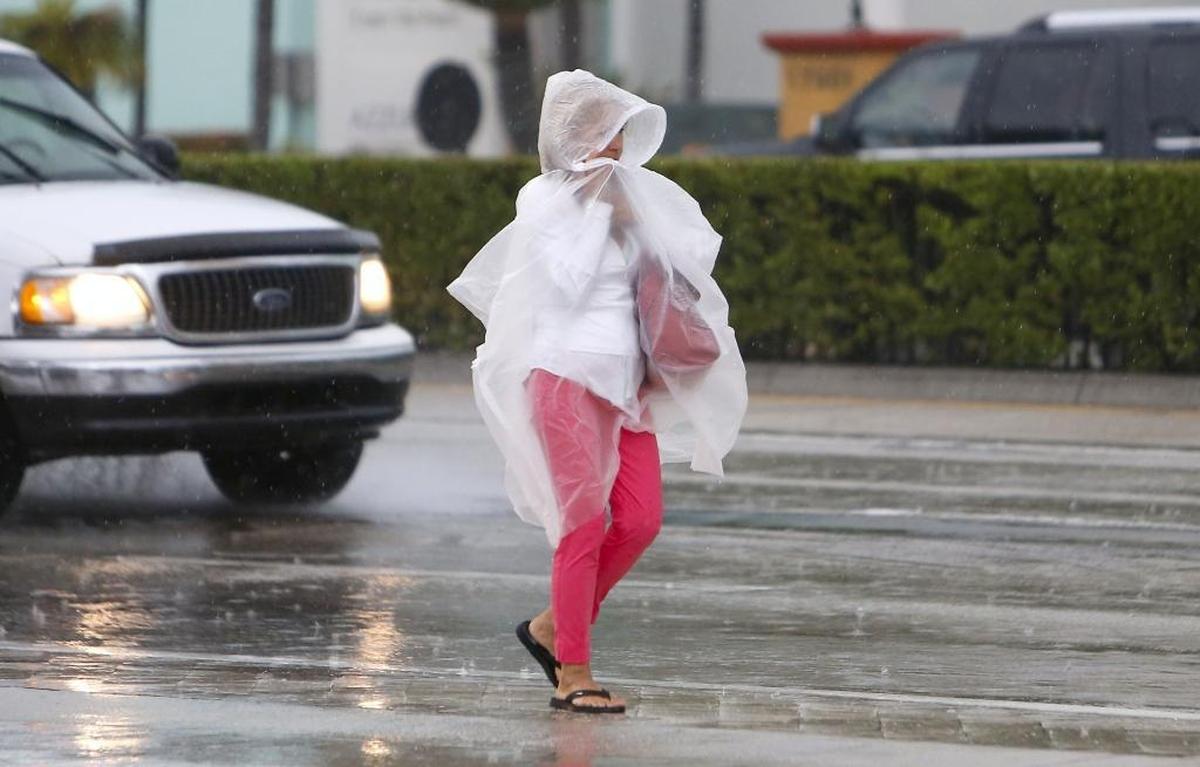 A woman covered from the rain as she walks at Collins Avenue on Tuesday, June 6, 2017, in Sunny Isles Beach.