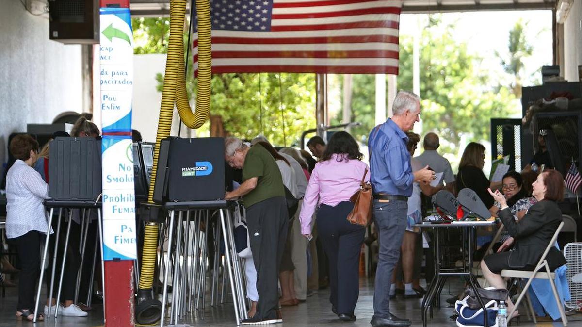 Poll workers help people to check in as voters mark their ballots at Miami Beach Fire Station #3 during the midterm election on Tuesday, Nov. 6, 2018.
