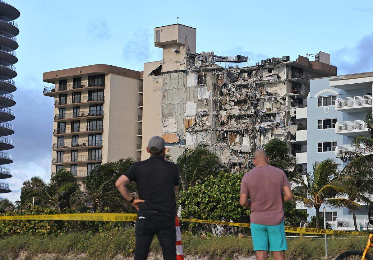 La gente observa los escombros del  Champlain Towers South Condo in Surfside, en 8777 Collins Avenue, que se derrumbó parcialmente a primeras horas del jueves en Surfside, Florida, el hueves 24 de junio de 2021.