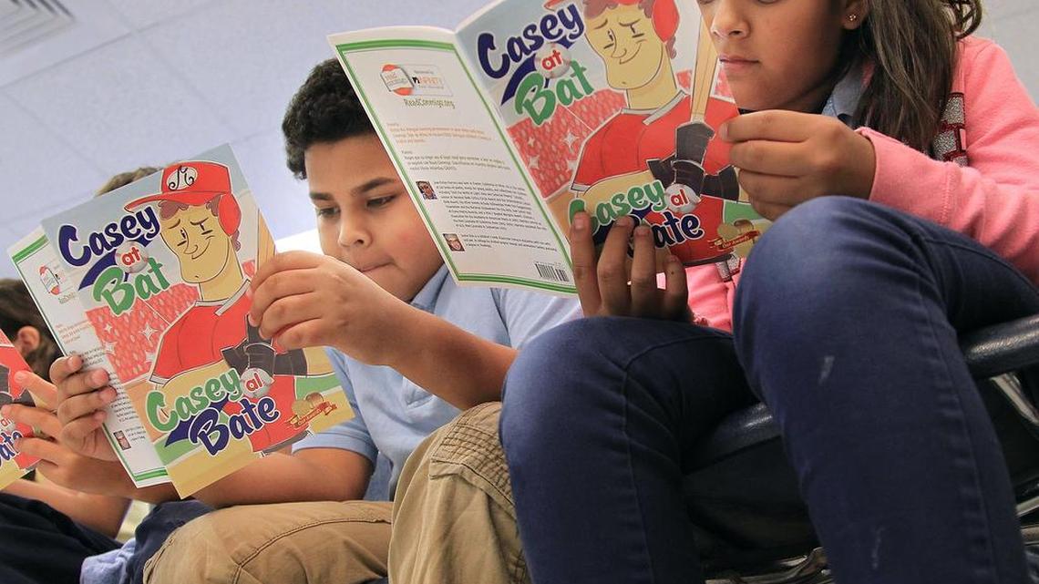 Fourth-graders Miguel Igualas, 10, and Diamond Fonseca, 10, read along with Miami Marlins center-fielder Marcell Ozuna (not pictured) during his visit to their classroom at Kensington Park Elementary for a bilingual reading session.