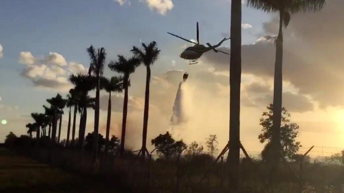 A Miami-Dade Fire Rescue helicopter drops water on a brush fire in Miramar Monday, April 11, 2016.