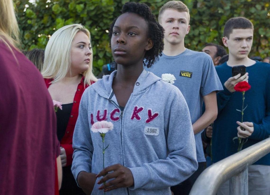 A woman holds a flower as she walks to Marjory Stoneman Douglas High School in Parkland on Wednesday, February 28, two weeks after Nikolas Cruz gunned down 17 people.