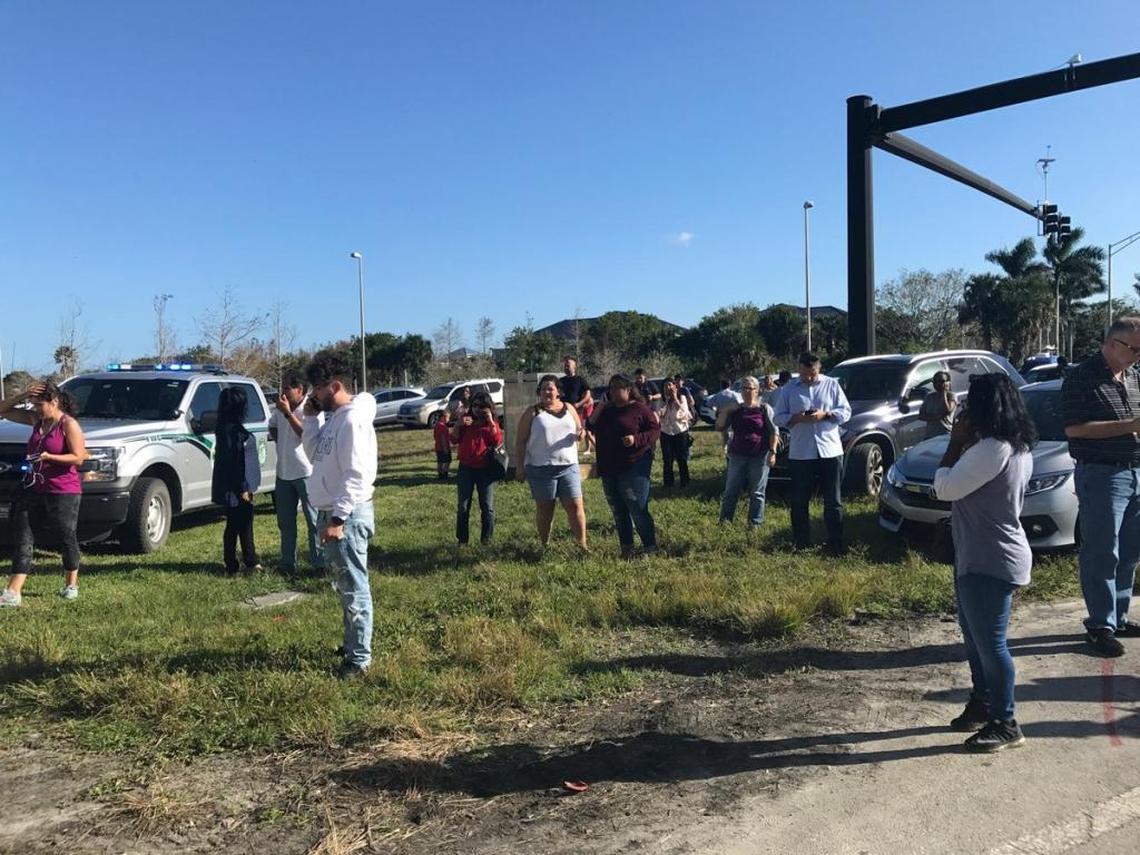 Parents are standing about a mile from Marjory Stoneman Douglas High as they try to calm their children by phone.