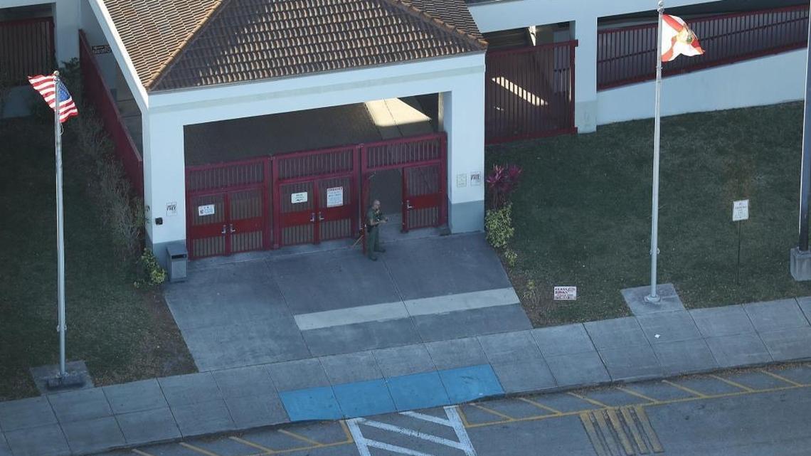 A law enforcement officer stands at the front door of the Marjory Stoneman Douglas High School in Parkland the day of the shootings at the school that left 17 people dead. Florida legislators say the building must be torn down.
