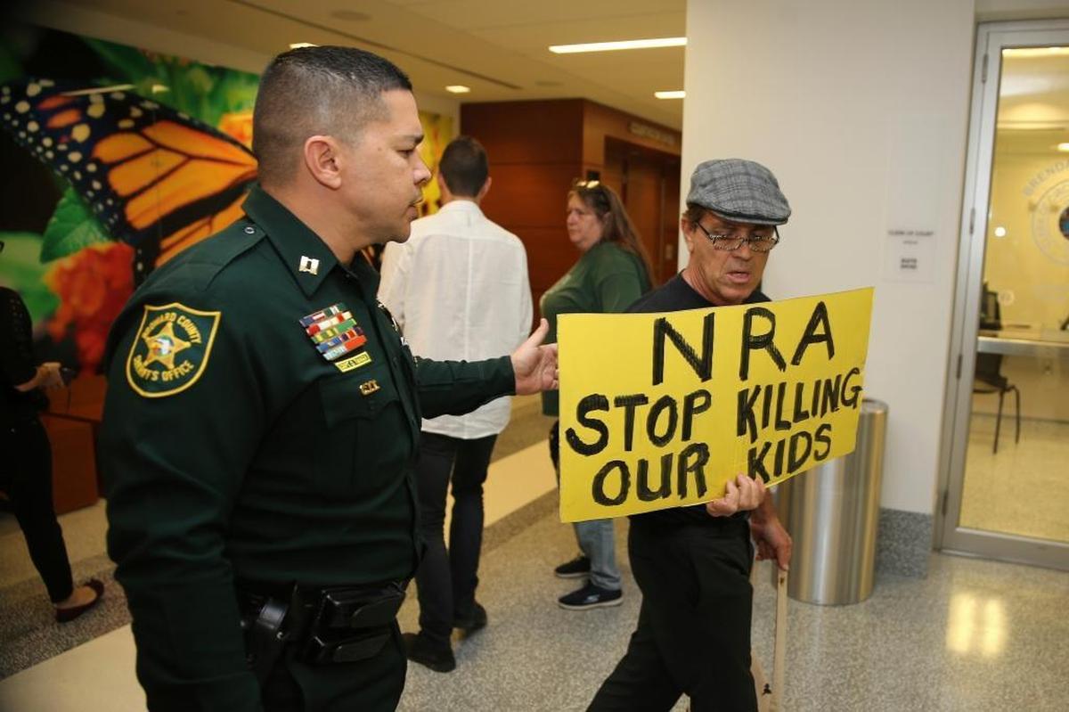 A Broward County sheriff's deputy escorts a protester away from the door of the courtroom where a hearing was held for school shooting suspect Nikolas Cruz, Thursday, Feb. 15, 2018, at Broward County Court in Fort Lauderdale.