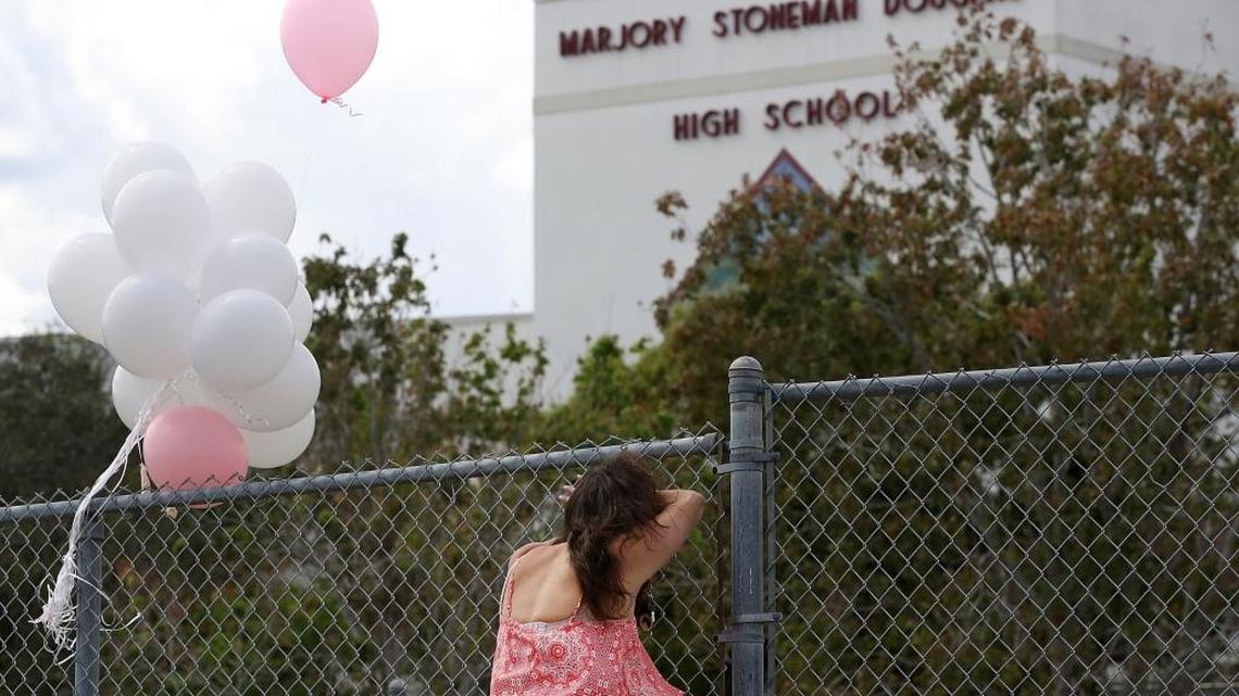 Angela Tanner rests against the fence that surrounds the Marjory Stoneman Douglas High School, on Feb. 18, 2018, in Parkland. The school will reopen to students on Wednesday, Feb. 28, 2018.