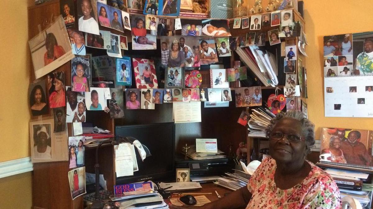 
Velmina Williams-Hamilton surrounded by pictures of her own family and children she knows from the community. She says her grandmother and cousins are buried at a former cemetery in Deerfield Beach where the black community was allowed to bury its dead. 
