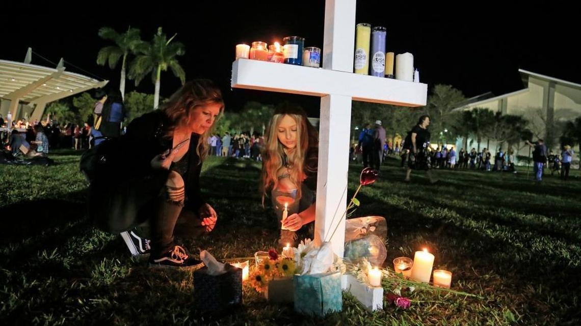 Attendees place candles on a cross at Pine Trails Park and Amphitheater after a vigil for the shooting victims at Marjory Stoneman Douglas High School in Parkland.