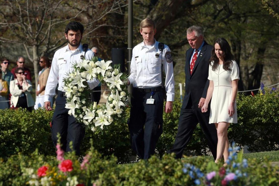 Members of the Virginia Tech Rescue Squad carry a wreath presented by then-Virginia Gov. Terry McAuliffe, second right, and his daughter Dori McAuliffe, right, on the Virginia Tech campus in Blacksburg, Virginia, on Sunday, April 16, 2017, during a 10th anniversary observance of the mass shooting that killed 32 plus the shooter.