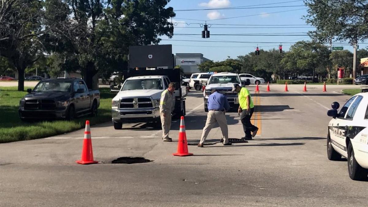 Pembroke Pines workers use cones to mark a sink hole that opened up on an access road just south of Pines Boulevard.