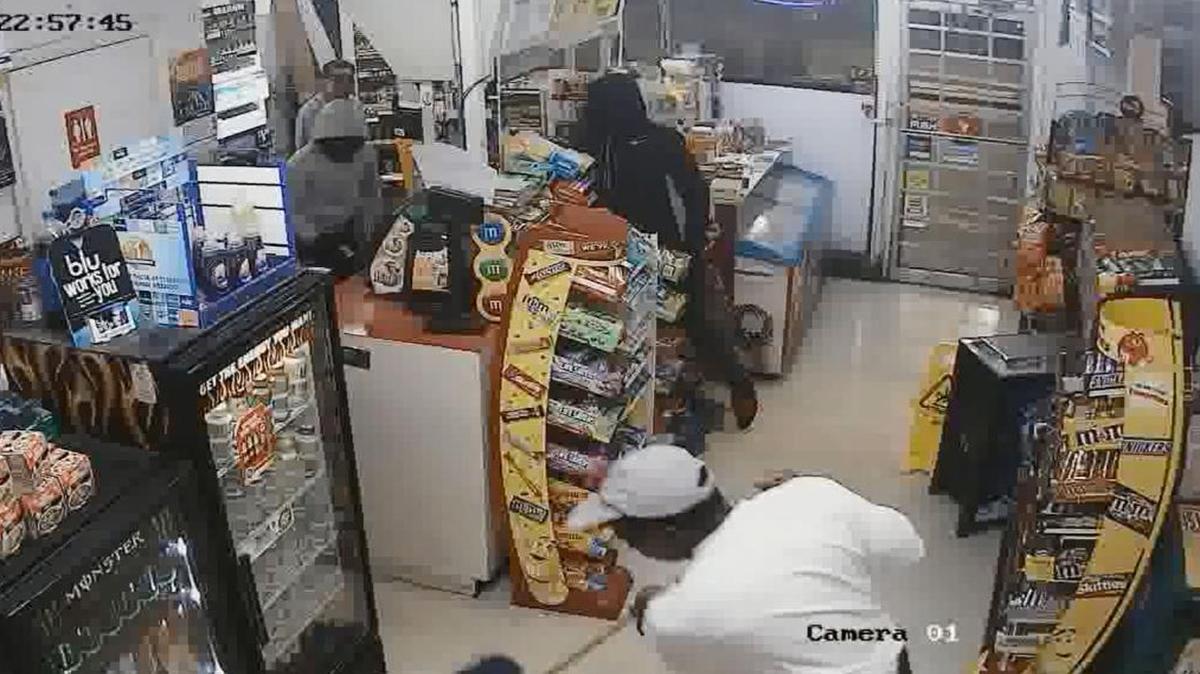 A convenience store employee continues to clean while armed robbers steal from the Express Gas Food Mart in Dania Beach.