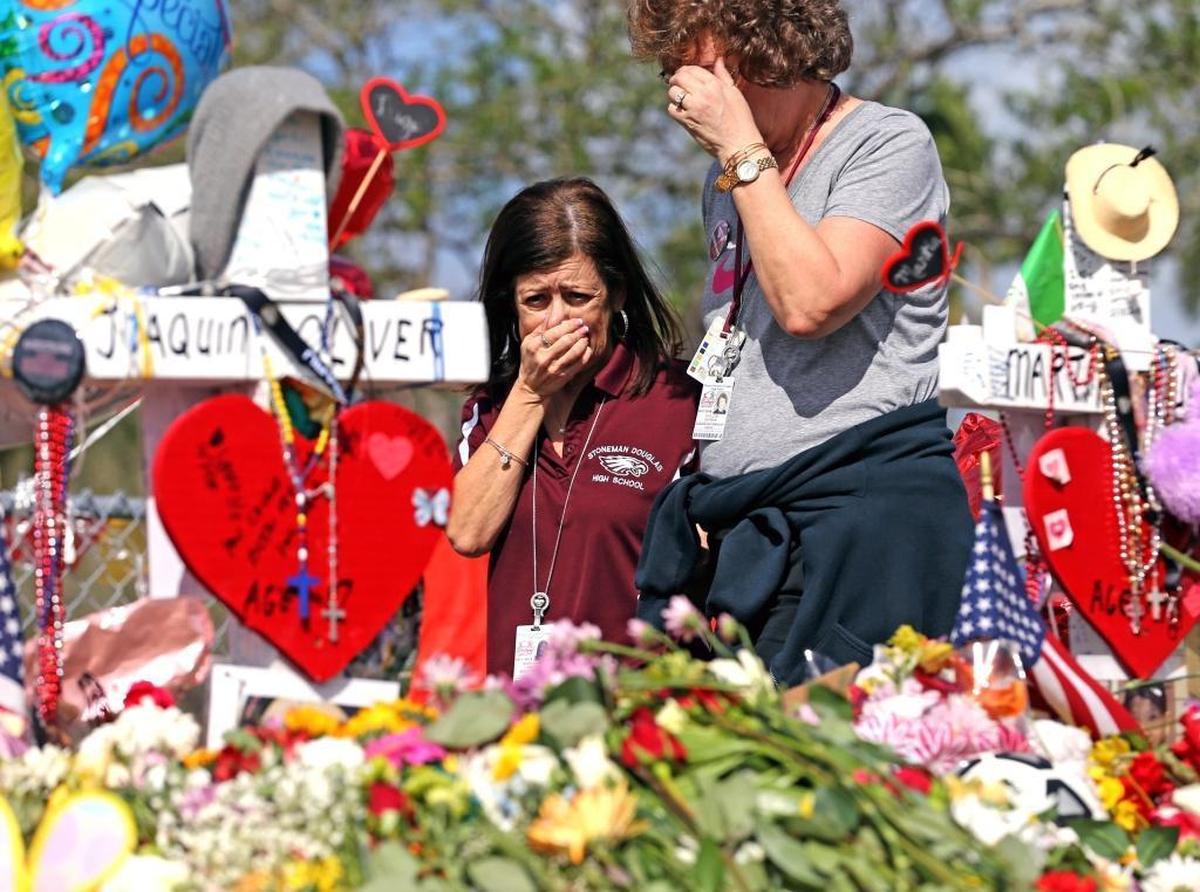 Marjory Stoneman Douglas High School office workers Margarita LaSalle, left, and JoEllen Berman walk along the hill lined with 17 crosses to honor the students and faculty members killed Feb. 14. Teachers and staff returned to the school on Friday, Feb. 23, 2018.