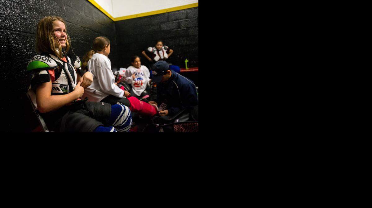 
Pines Ice Divas player Madelyne Pope of Pembroke Pines, left, speaks with teammates and coach Pat Dray helps tie the skates of his daughter, Emily Dray of Surfside, before their game against the Red Wings in Pembroke Pines on Sunday, Dec. 14, 2014.

