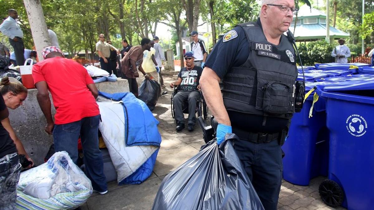 Ft. Lauderdale police officer George Stengel helps clear the homeless camp in front of the library in downtown.