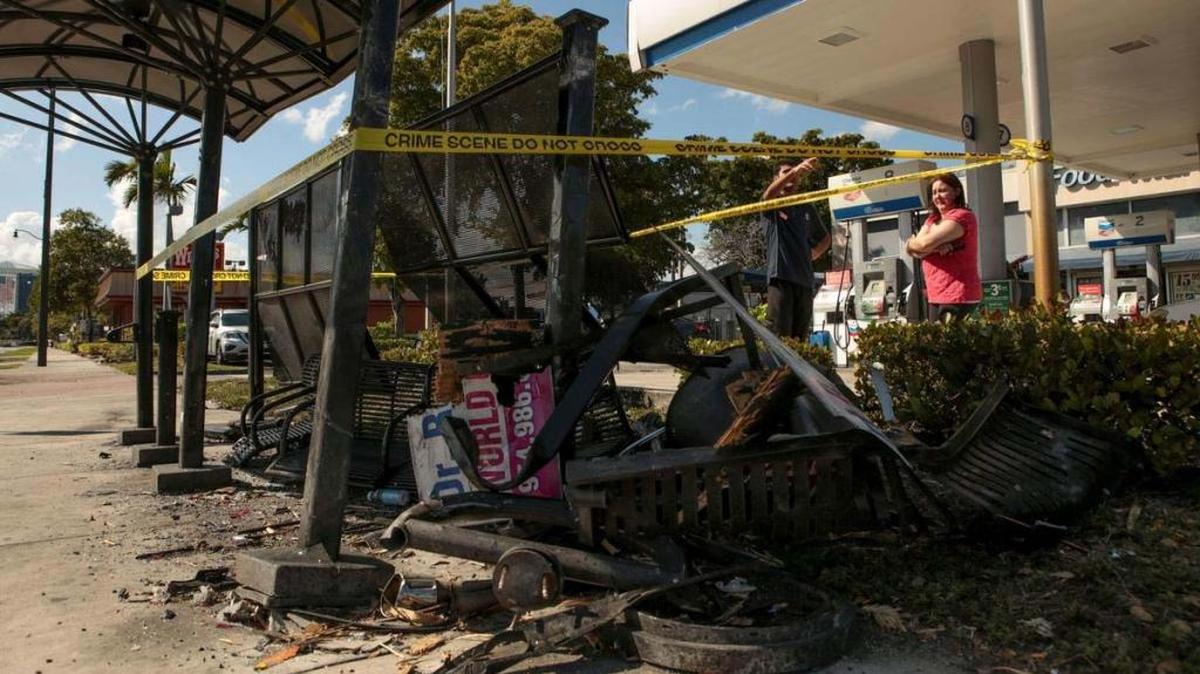Ahmer Tahir, left, and Claudia De La Garza, right, look at the scene where a fiery crash occurred near the Chevron gas station on the corner of Hollywood Boulevard and North 35th Avenue in Hollywood early Feb. 26.