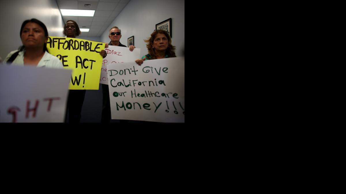 
Ruby Edwards (rear L), Juan Gonzalez (rear R) and other protesters gather in the office of Florida State Rep. Manny Diaz as they protest his stance against the expansion of Medicaid eligibility rules on September 20, 2013, in Miami. 
