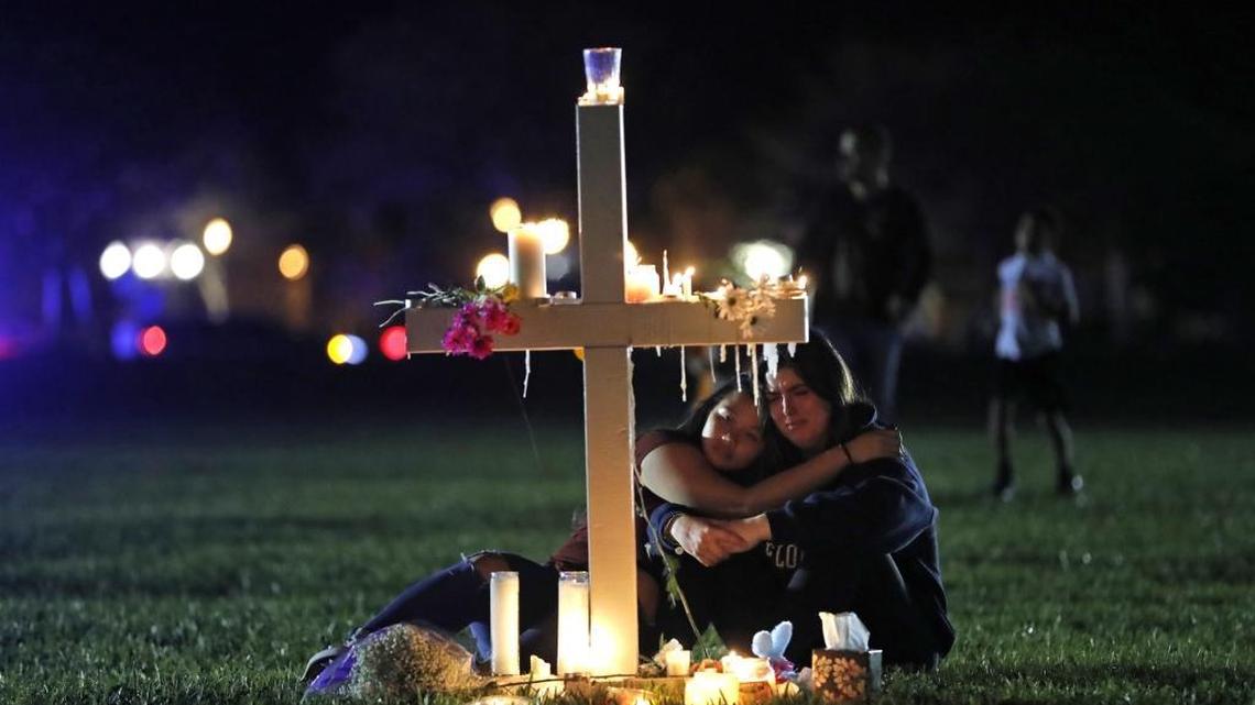 Two people comfort each other as they sit and mourn at one of 17 crosses after a candlelight vigil for the victims of the Wednesday shooting at Marjory Stoneman Douglas High School, in Parkland on Thursday, Feb. 15, 2018. Nikolas Cruz, a former student, has been charged with 17 counts of premeditated murder.