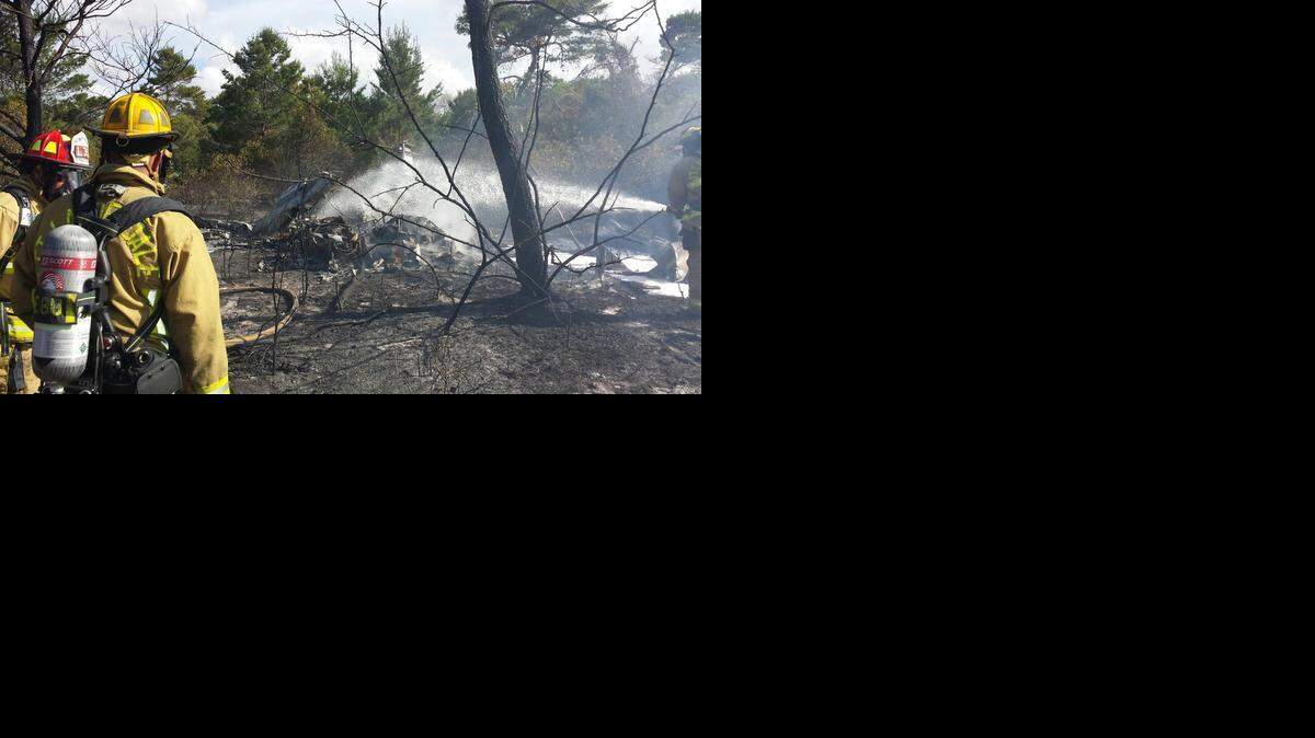 
THE WRECKAGE: Fort Lauderdale Fire rescue workers douse the flames on a Piper Navajo aircraft that crashed into a wooded nature preserve a quarter mile from the Fort Lauderdale Executive Airport Sunday afternoon. All four passengers were killed.
