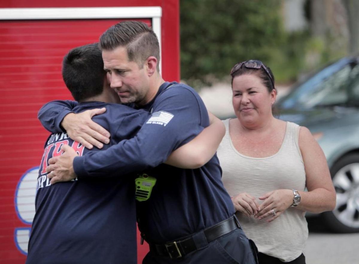 Jason Valentine of Coral Springs Parkland Fire Rescue hugs shooting survivor Kyle Laman as his mom, Marie Laman, looks on during a visit to the Lamans' Coral Springs home on April 25. Kyle, who dreams of one day becoming a firefighter, was gravely wounded in the Feb. 14 shooting at Marjory Stoneman Douglas High School.