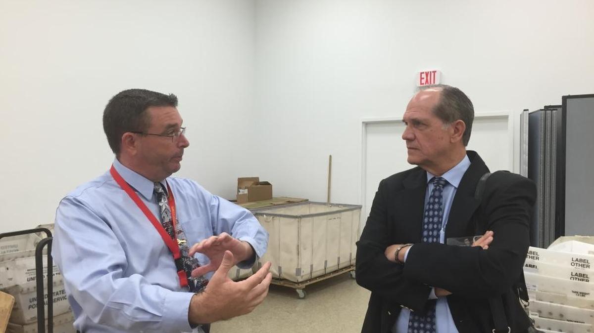 Broward Canvassing Board member Judge John D. Fry (L) explains how absentee ballots are processed and authenticated Thursday at the supervisor of elections headquarters to David Shestokas, an attorney with the Republican National Lawyers Association.