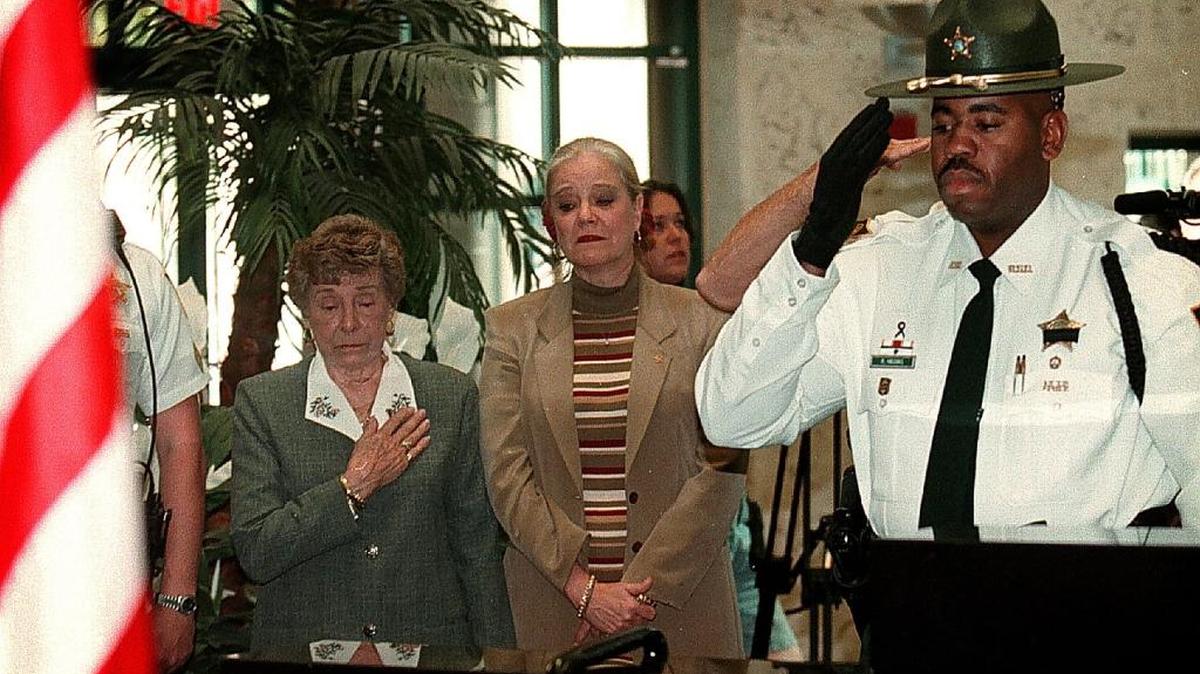 The Broward Sheriff’s Office held a short ceremony, Feb. 18, 2000, to remember Deputy John Greeney on the 10th anniversary of his being killed in the line of duty. Pictured is Greeney’s mother, Theresa Greeney, and his sister, Pat Hubrig. Honor guard deputy Raymond Higgins salutes the wreath placed by Greeney’s photo in the atrium of the Public Safety Building on West Broward Blvd.