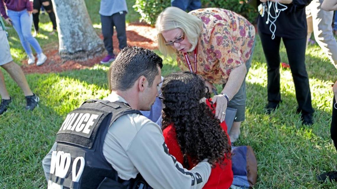 A traumatized Marjory Stoneman Douglas student is assisted by a law enforcement officer after she and hundreds of classmates were able to flee the high school where Nikolas Cruz opened fire with an AR-15 semiautomatic rifle, killing 17, on Feb. 14.
