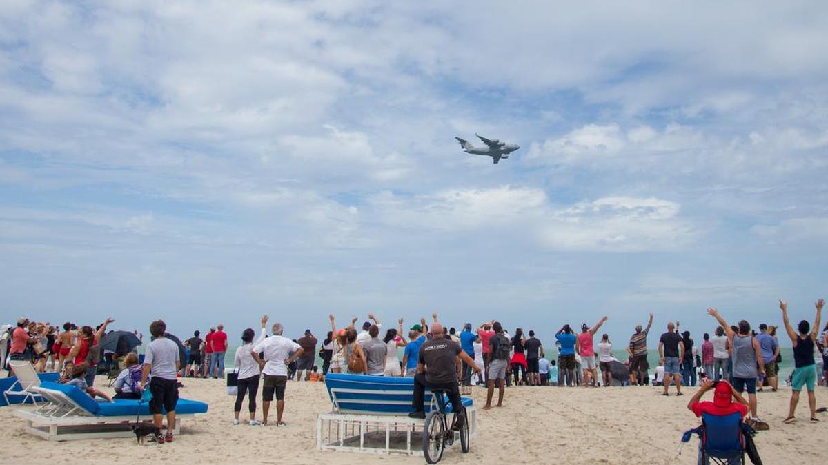 A crowd of people waves at a United States Air Force plane flying over the beach during the Hyundai Air & Sea show in Miami Beach on Sunday, May 27, 2018.