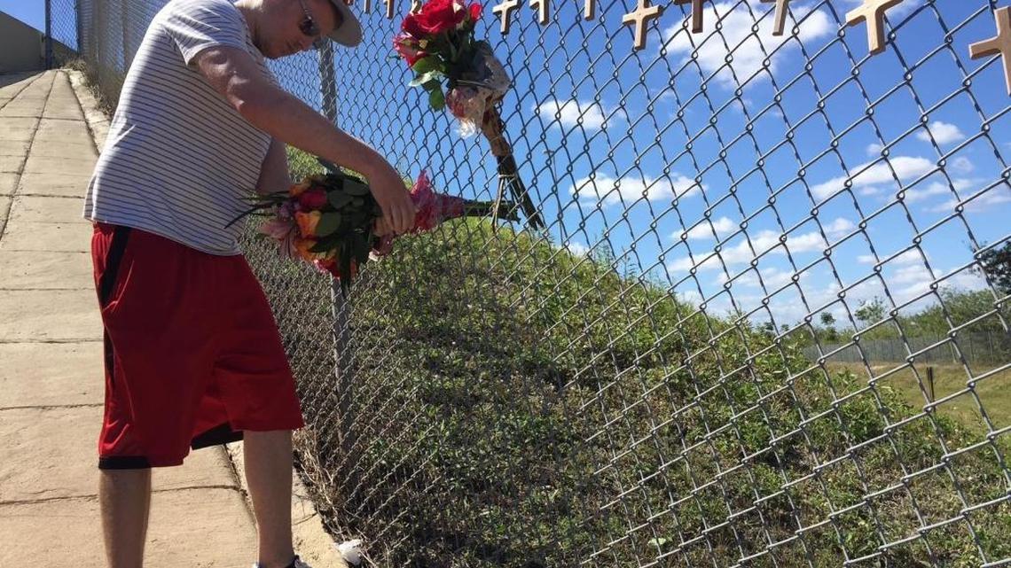 Jason Price, a former student at Marjory Stoneman Douglas High School (Class of 2005), leaves flowers at a makeshift memorial near the campus.