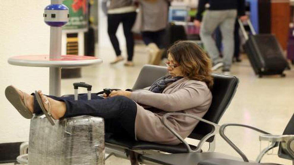 
Carmen Rodriguez rests her feet Monday morning as she waits for her flight to Madrid at Miami International Airport, Nov. 24, 2014.
