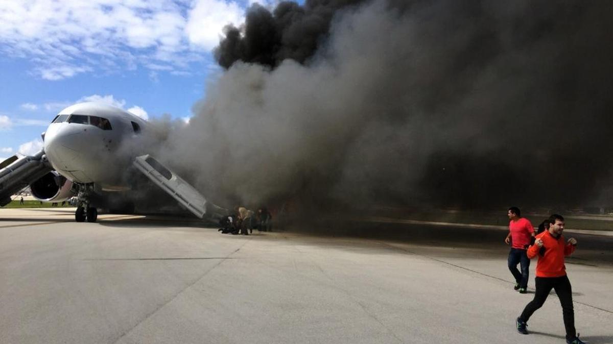 Passengers are evacuated from a plane on fire at Fort Lauderdale-Hollywood International Airport on Thursday, Oct. 29, 2015.