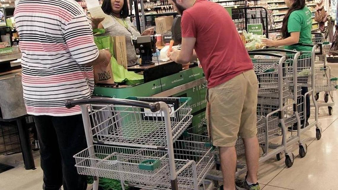 Instacart’s Joel King, left, Louna Nelson, David Lipkin and Claudia Rodas complete Instacart customers’ orders in the Whole Foods Market in downtown Miami.
