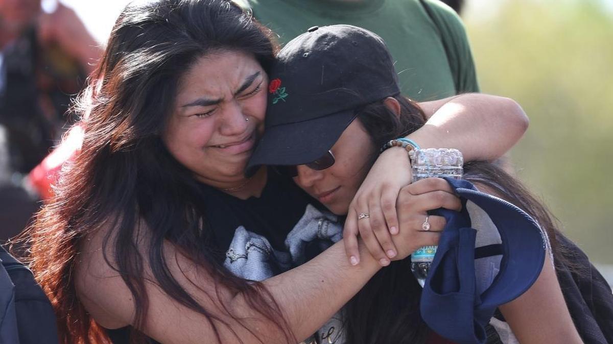 Fernanda Mora, left, an alumna from Deerfield Beach High School, and Vallery Cruz, a senior at the school, hug in front of Marjory Stoneman Douglas High School at an event to support victims.