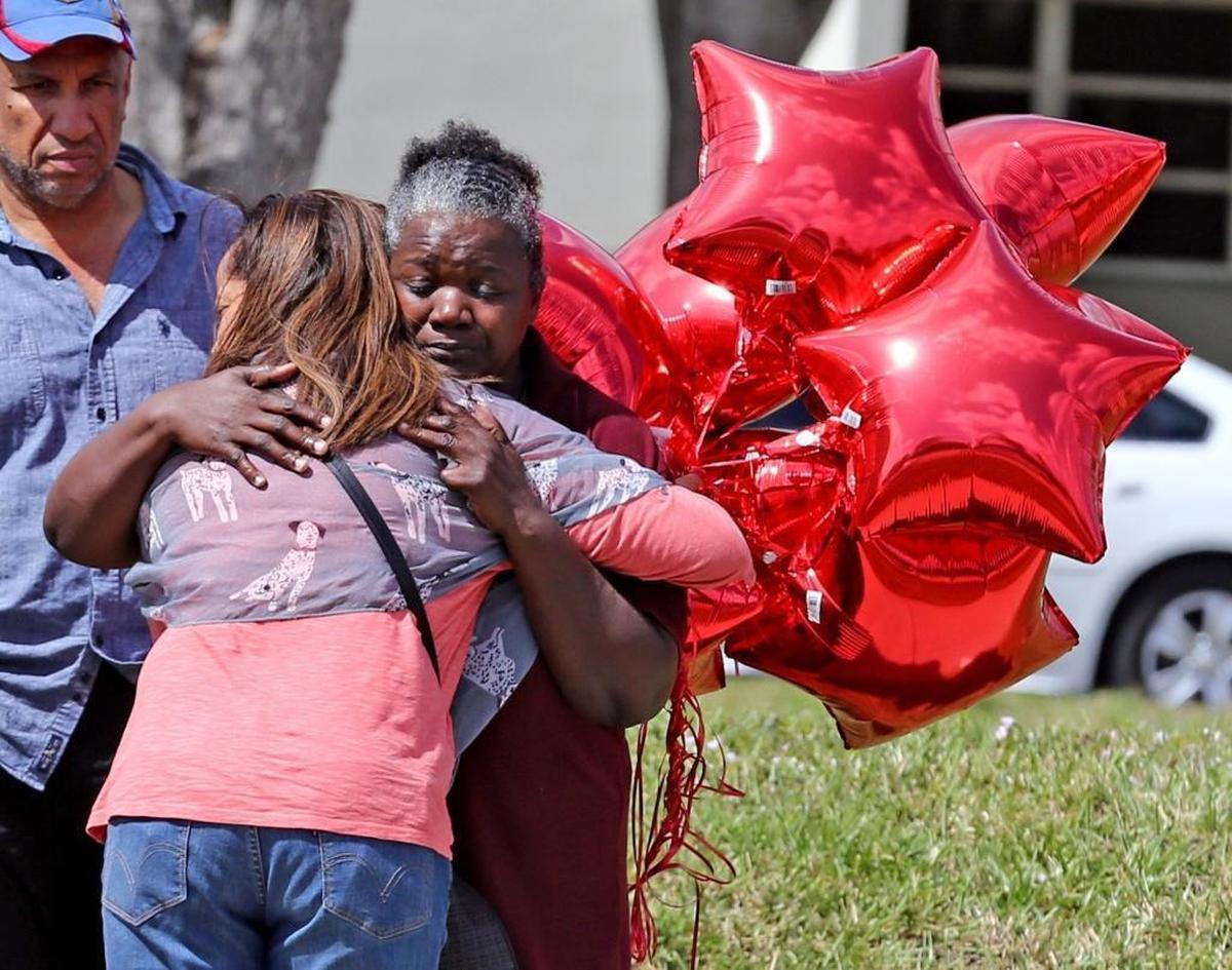 School bus driver Pearlie Corker gets a hug at Marjory Stoneman Douglas High School as teachers and staff returned on Friday, Feb. 23, 2018. Corker said she had arrived at the school as the shooting began Feb. 14 and stayed on the bus in front of the school praying for the students and teachers.