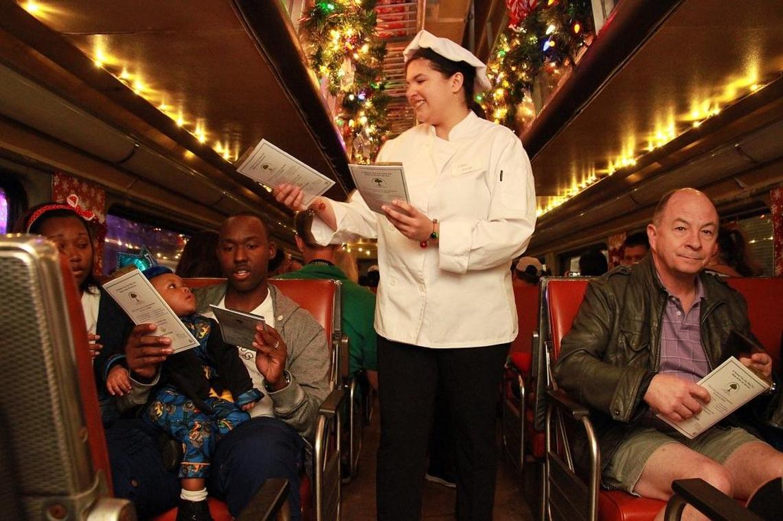 Leah Nadell, acting as one of the chefs, hands out Christmas carol song books to passengers on the first night of the Polar Express Train Ride’s visit to Miami at the Gold Coast Railroad Museum in West Kendall, on Nov. 27, 2015.