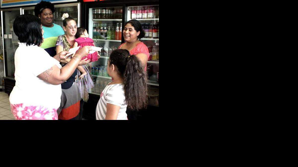 
Jenifer Orozco, right back, and her children accept the donations from the staff at Laurie's Deli Tuesday. Deli owner Laurie Temcelski chose Orozco's family to 'adopt' for Christmas.
