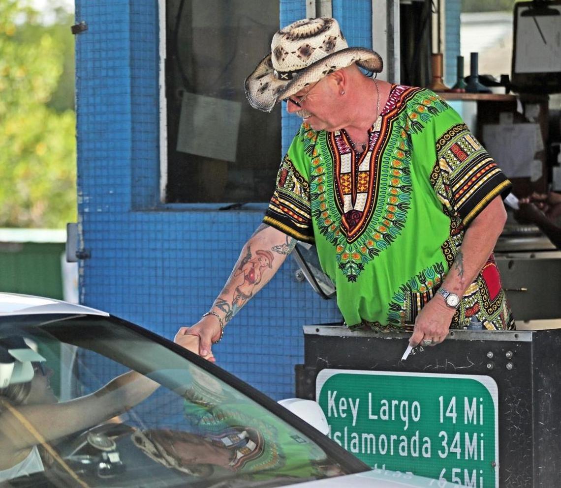 Toll collector Ken Murray, known as ‘Cowboy,’ says goodbye to a commuter friend on his last day of work after 25 years collecting tolls at the Card Sound Road toll booth, which shut down on Thursday, Aug. 31, 2017, due to electronic tolling.