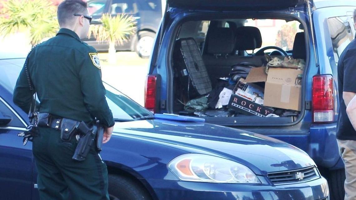 A Monroe County Sheriff’s Office deputy stands behind a blue Dodge SUV in the Burger King parking lot at mile marker 99 in Key Largo Sunday. At least one person in the vehicle is wanted on federal explosives charges in Tampa.