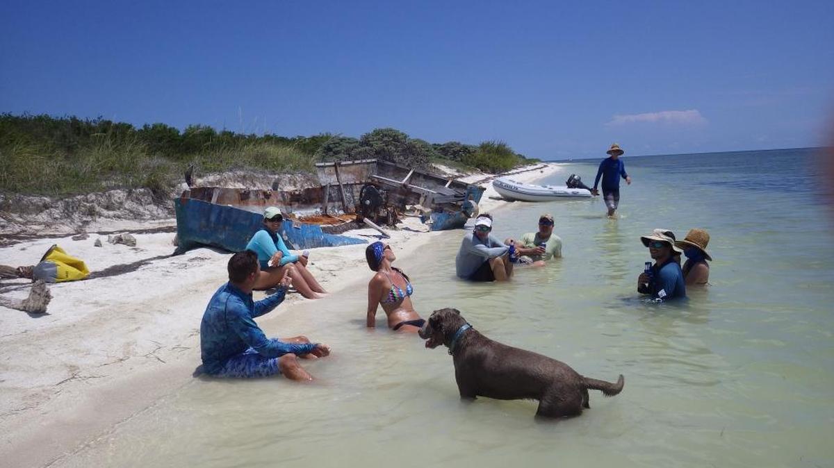 Bathers hang out alongside an abandoned boat used by migrats to cross the Florida Straits. Recently, a team of marine salvors removed a total of 31 boats littering the Marquesas, a group of islands about 20 miles west of Key West.