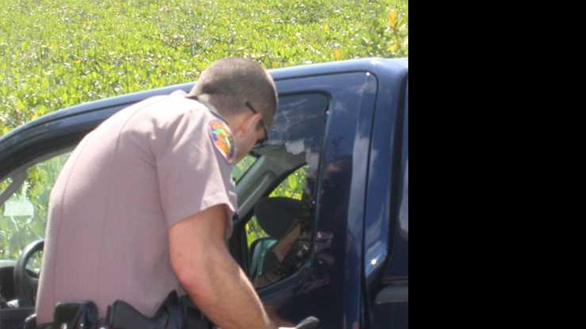 
Florida Highway Patrol Trooper Andrew Dunn looks in a pickup truck that crashed through the fence on the 18-Mile Stretch last August. Dunn was disciplined by the FHP following a complaint from a sergeant that he didn't do enough to try saving the driver of the vehicle. 
