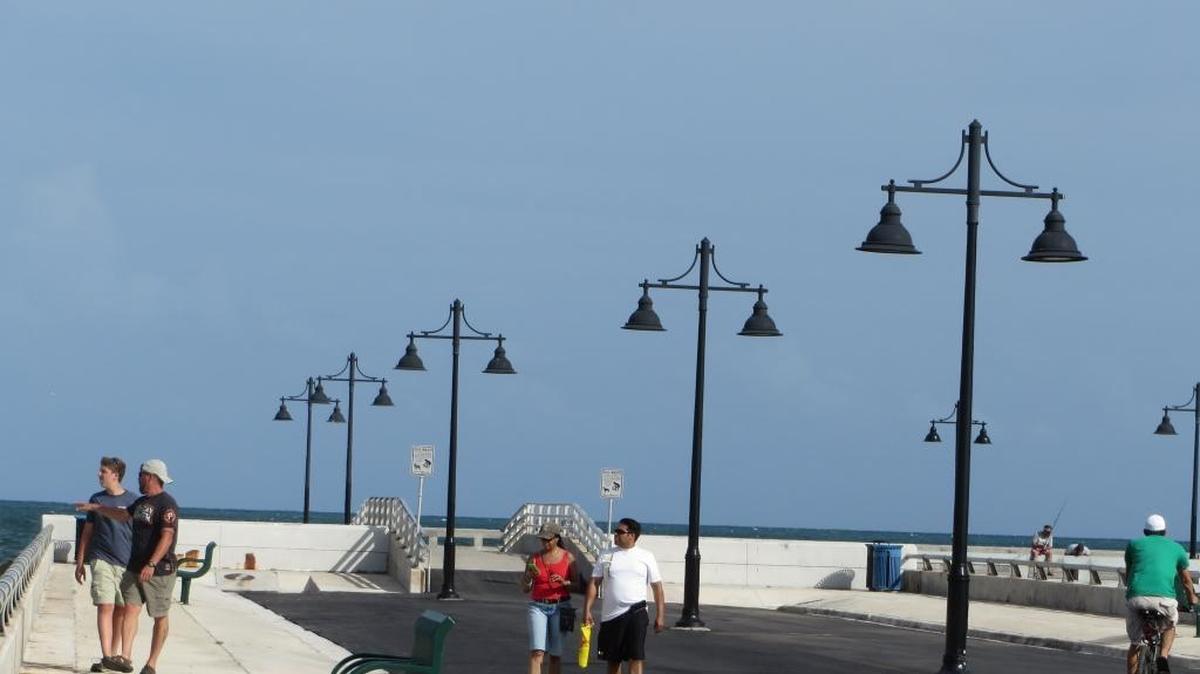 People stroll along the freshly paved White Street Pier, which the city calls a needed improvement while many locals say it was a mistake.