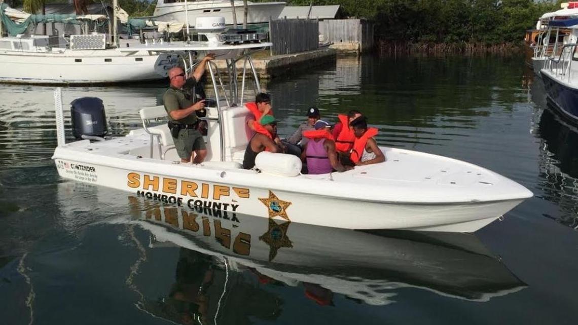 Monroe Deputy Joe Riggs escorts migrants in a sheriff’s office boat on Monday morning.