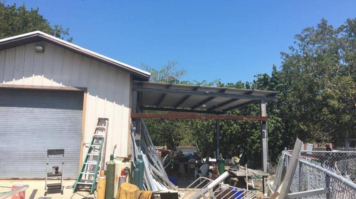 A hole, the result of a reported explosion this morning, is slightly visible in the roof of the carport-like structure at Marathon Electric Sign & Light.